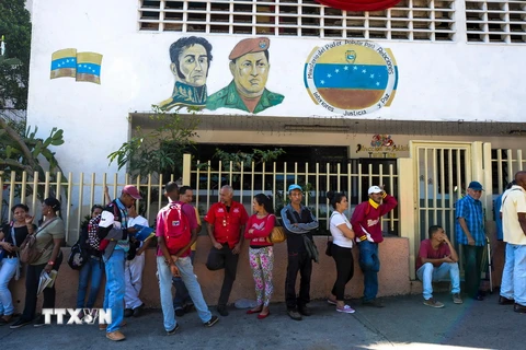 Người dân Venezuela xếp hàng chờ đổi tiền bên ngoài ngân hàng trung ương ở Caracas ngày 16/12. (Nguồn: AFP/TTXVN)