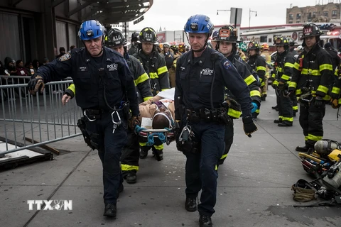 Nhân viên thuộc Sở Cứu hỏa và Sở Cảnh sát thành phố New York chuyển người bị thương khỏi hiện trường vụ tai nạn hôm 4/1. (Nguồn: AFP/TTXVN)