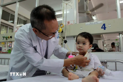 Bác sỹ Nguyễn Thế Huy, Phó trưởng khoa Tai Mũi Họng, Bệnh viện Nhi đồng 1 Thành phố Hồ Chí Minh thăm khám cho bệnh nhi. (Ảnh: Phương Vy/TTXVN)