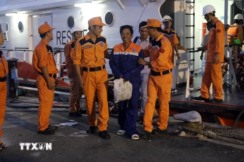 Các ngư dân được lực lượng cứu hộ đưa lên bờ an toàn. (Ảnh: Đoàn Mạnh Dương/TTXVN)