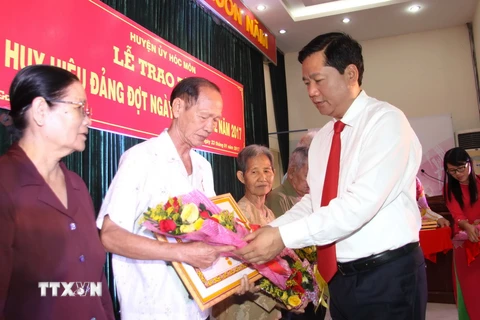 Ông Đinh La Thăng, Ủy viên Bộ Chính trị, Bí thư Thành ủy Thành phố Hồ Chí Minh trao huy hiệu 70 năm tuổi đảng cho các vị lão thành cách mạng. (Ảnh: Thanh Vũ/TTXVN)