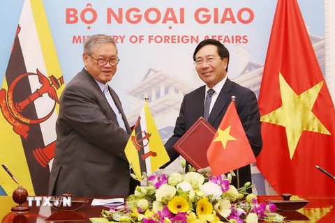 Phó Thủ tướng Phạm Bình Minh với Bộ trưởng Ngoại giao và Thương mại Brunei Hon.Pehin Dato Lim Jock Seng trao đổi biên bản thỏa thuận tại kỳ họp. (Ảnh: Nguyễn Dân/TTXVN)
