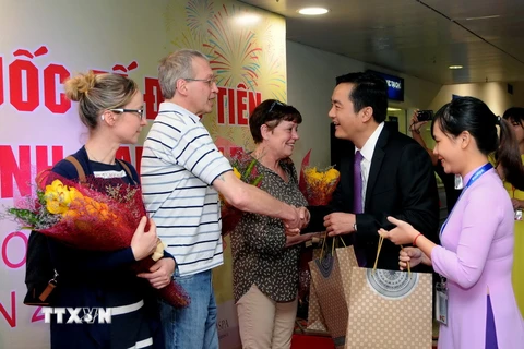 Ông Bùi Tá Hoàng Vũ, Giám đốc Sở du lịch Thành phố Hồ Chí Minh tặng quà cho đoàn khách du lịch quốc tế đầu tiên trong năm 2017. (Ảnh: An Hiếu/TTXVN)