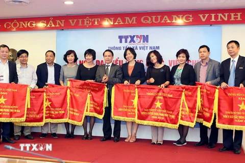 Tổng Giám đốc TTXVN Nguyễn Đức Lợi trao cờ thi đua của ngành cho các tập thể có nhiều thành tích xuất sắc trong phong trào thi đua năm 2016. (Ảnh: Thành Đạt/TTXVN)