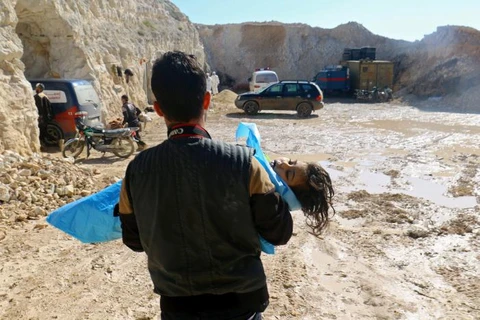 Một người đàn ông mang thi thể một em bé bị chết ngạt trong vụ tấn công ở Idlib. (Nguồn: Reuters)