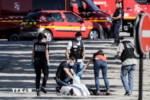 Cảnh sát khám nghiệm hiện trường trên đại lộ Champs-Elysees ở Paris sau vụ xe ôtô lao vào xe cảnh sát ngày 19/6. (Nguồn: AFP/TTXVN)