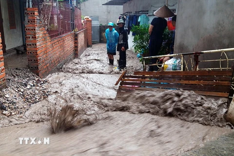 Nước chảy xiết kéo theo đất sỏi khiến việc đi lại của người dân gặp khó khăn. (Ảnh: Nguyễn Hoàng/TTXVN)