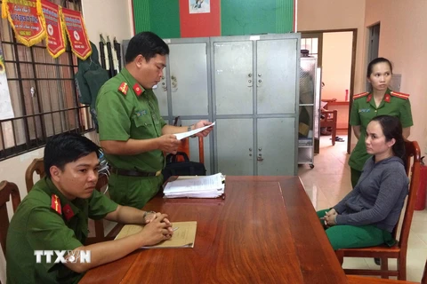 Cảnh sát điều tra Công an tỉnh Trà Vinh đọc lệnh bắt tạm giam bị can Nguyễn Thị Phượng Anh. (Ảnh: Thanh Hòa/TTXVN)