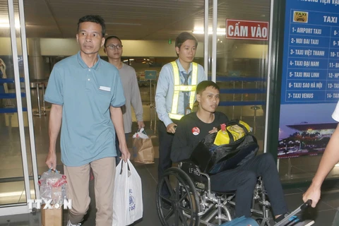 Ba thuyền viên Bùi Xuân Viện (áo xanh), Bùi Trung Đức (áo đen ngồi xe)và Nguyễn Quang Huy (hàng sau) về đến Sân bay quốc tế Nội Bài. (Ảnh: Doãn Tấn /TTXVN)