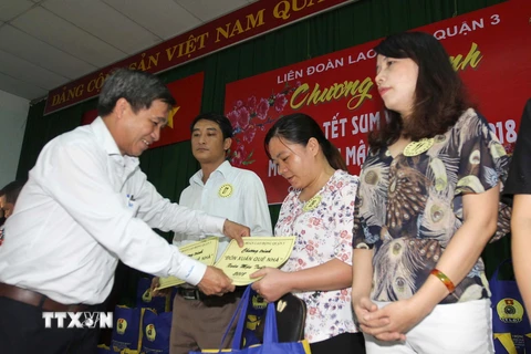 Lãnh đạo Liên đoàn lao động Thành phố Hồ Chí Minh trao tặng quà và vé xe cho công nhân, viên chức, lao động khó khăn sáng 27/1. (Ảnh: Thanh Vũ/TTXVN)
