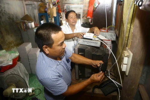 Lắp đặt đầu thu truyền hình số mặt đất cho hộ gia đình ở Hà Nội. (Ảnh: Minh Quyết/TTXVN)