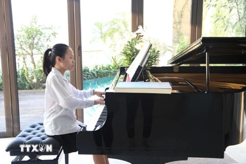 Trần Minh Châu bên cây đàn piano. (Ảnh: Nguyễn Văn Cảnh/TTXVN)