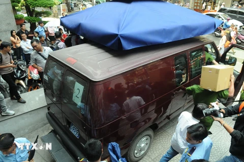 Xe của Cơ quan Cảnh sát điều tra Bộ Công đưa hai nhân viên Eximbank Chi nhánh Thành phố Hồ Chí Minh rời khỏi trụ sở Eximbank Chi nhánh Thành phố Hồ Chí Minh (trưa 26/3). (Ảnh: Thành Chung/TTXVN)