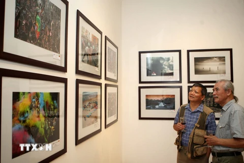 Nghệ sỹ nhiếp ảnh và khách tham quan triển lãm. (Ảnh: Thanh Tùng/TTXVN)