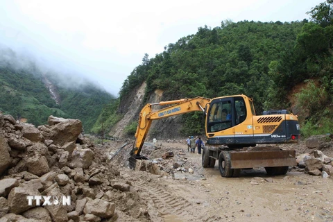 Máy móc san gạt bùn, đất đá bị sạt lở tại km75, Quốc lộ 4D từ Lai Châu đi Lào Cai. (Ảnh: Quý Trung/TTXVN)