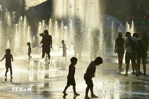 Trẻ em chơi đùa bên vòi phun nước để tránh nắng nóng tại Montreal, Canada ngày 3/7. (Nguồn: AFP/TTXVN)