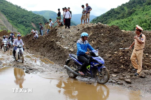 Cảnh sát giao thông tỉnh Lai Châu hướng dẫn người dân đi lại trên tuyến Quốc lộ 12 bị sạt lở đất đá. (Ảnh: Công Tuyên/TTXVN)