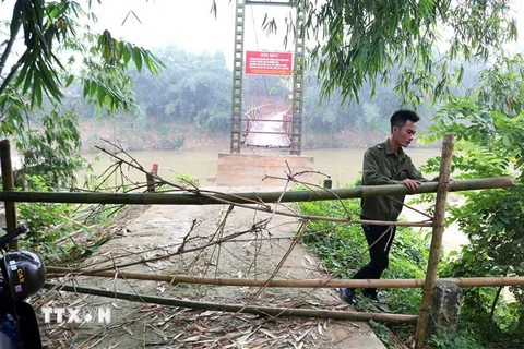 Do cầu treo bị hư hỏng nặng, rất nguy hiểm, nên xã Văn Luông đã cắt cử lực lượng công an xã ứng trực bên cầu, ngăn người dân không bắc thang leo lên cầu để qua sông. (Ảnh: Trung Kiên/TTXVN)