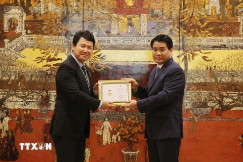 Chủ tịch Ủy ban Nhân dân thành phố Hà Nội Nguyễn Đức Chung (phải) trao Bằng khen cho ông Katsuro Nagai. (Ảnh: Nguyễn Văn Cảnh/TTXVN)