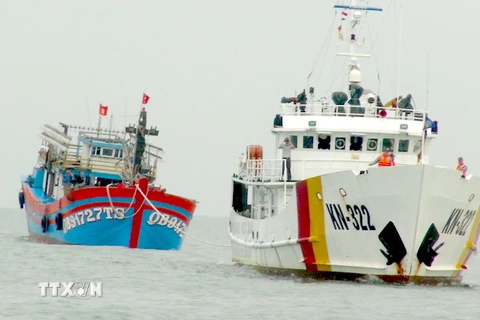Tàu KN 322 thuộc Chi đội Kiểm ngư số 3 lai dắt tàu cá bị nạn cùng 19 ngư dân vào bờ an toàn. (Ảnh: Đức Thọ/TTXVN)