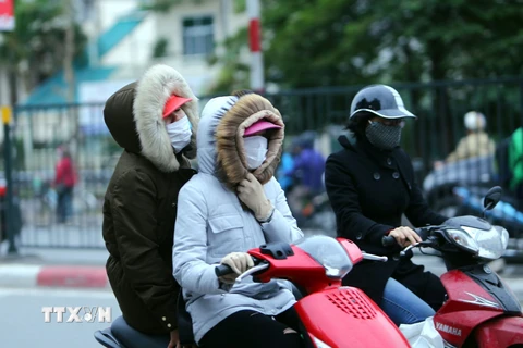 Người dân Hà Nội trang bị áo ấm chống rét, trên đường Giải Phóng (Hà Nội). (Ảnh: Danh Lam/TTXVN)