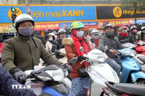 Người dân Hà Nội ra đường đều trang bị cho mình quần áo ấm, quấn khăn, đeo khẩu trang… để chống lại thời tiết lạnh buốt nhất là khi di chuyển bằng xe máy. (Ảnh: Quang Quyết/TTXVN)