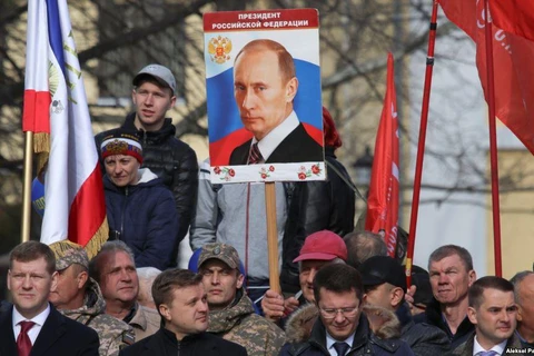 Một người đàn ông cầm tấm bảng với bức chân dung của Tổng thống Nga Vladimir Putin trong lễ kỷ niệm kỷ niệm 5 năm ngày Nga sáp nhập Crimea ở Simferopol vào ngày 15/3. (Nguồn: Reuters)