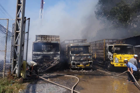 Vụ cháy làm 3 xe tải và nhiều tài sản khác bị thiêu rụi. (Ảnh: Bùi Giang/TTXVN)