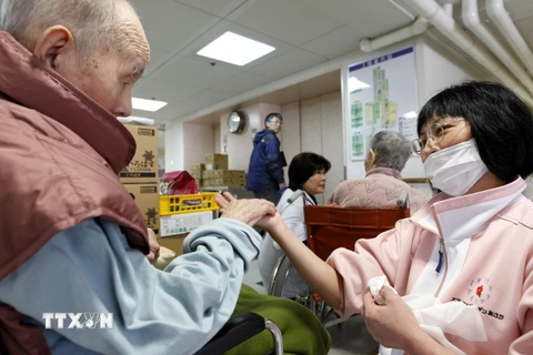 Điều dưỡng viên hỗ trợ người cao tuổi tại Tomioka, tỉnh Fukushima, Nhật Bản. (Nguồn: AFP/TTXVN)