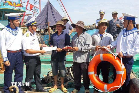 Cán bộ Bộ Tư lệnh Vùng 2 Hải quân tặng cờ Tổ quốc và phao cứu sinh cho ngư dân. (Ảnh: Huỳnh Ngọc Sơn/TTXVN)