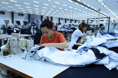 Công nhân sản xuất hàng may mặc tại Công ty trách nhiệm hữu hạn Kydo Việt Nam. (Ảnh: Phạm Kiên/TTXVN)