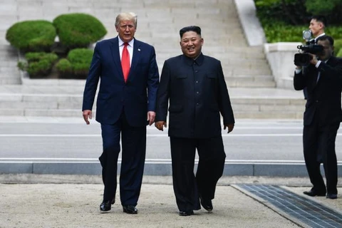 Tổng thống Mỹ Donald Trump và Nhà lãnh đạo Triều Tiên Kim Jong-un tươi cười bước chân trên lãnh thổ Triều Tiên ở DMZ. (Nguồn: Getty Images)