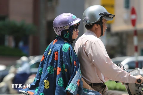 Người dân ra đường với trang phục kín mít để tránh cái nắng gay gắt. (Ảnh: Thành Đạt/TTXVN)