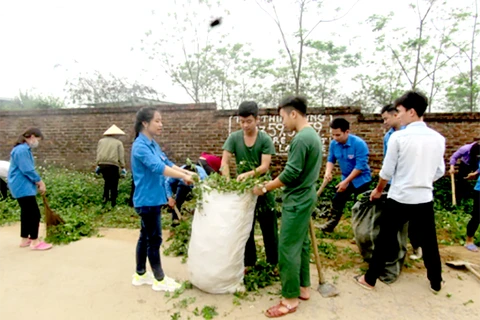 Chiến sỹ Trung đoàn 58 cùng đoàn viên thanh niên địa phương thực hiện vệ sinh môi trường đường làng, ngõ xóm. (Ảnh: Tiến Thành/Vietnam+)