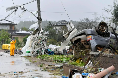 Một công nhân đứng giữa chụp ảnh những mảnh vỡ sau cơn bão Hagibis quét qua Ichihara, Chiba, gần Tokyo. (Nguồn: AP)