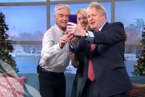 Hình ảnh Thủ tướng Johnson dùng điện thoại Huawei chụp ảnh tự sướng kỷ niệm với hai người dẫn chương trình. (Nguồn: https://twitter.com/johnestevens)