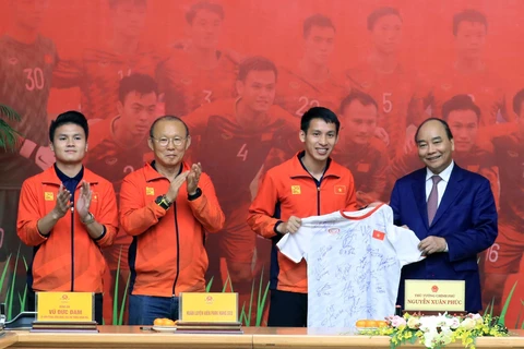 Tiền vệ Đỗ Hùng Dũng, thay mặt đội tuyển bóng đá U22 nam tặng Thủ tướng Nguyễn Xuân Phúc chiếc áo đấu có chữ ký của các cầu thủ và Ban huấn luyện. (Ảnh: Thống Nhất/TTXVN)