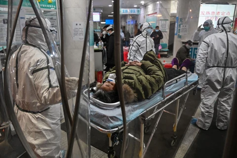 Nhân viên y tế, mặc quần áo bảo hộ vận chuyển bệnh nhân tại Bệnh viện Chữ Thập đỏ Vũ Hán ở Vũ Hán vào ngày 25/1. (Nguồn: Getty Images)
