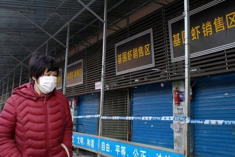 Một người phụ nữ đeo khẩu trang đi qua khu chợ hải sản đã bị đóng cửa ở Vũ Hán. Đây được cho là nơi khởi phát dịch viêm phổi cấp do chủng mới corona. (Nguồn: AFP)