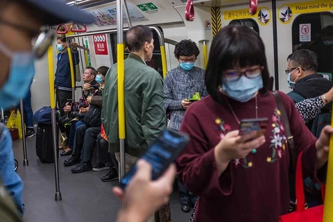 Người dân đeo khẩu trang và dùng điện thoại trên tàu điện ngầm ở Trung Quốc. (Nguồn: AFP)
