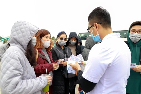 Cán bộ nhân viên Trung tâm Kiểm soát bệnh tật tỉnh Quảng Ninh truyền thông trực tiếp về nCov đến khách du lịch. (Nguồn: TTXVN phát)