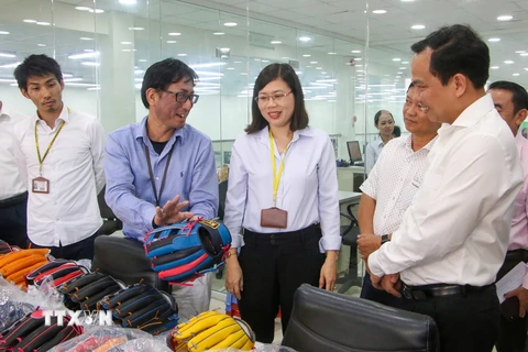 Ông Nakamura, Tổng Giám đốc Công ty trách nhiệm hữu hạn Quốc tế Tri Việt (Khu Công nghiệp Trà Nóc) giới thiệu sản phẩm găng tay bóng chày xuất khẩu của công ty với lãnh đạo thành phố Cần Thơ. (Ảnh: Thanh Liêm/TTXVN)