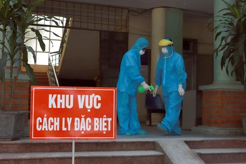 Các y bác sỹ Phòng khám Đa khoa khu vực Quang Hà mặc đồ bảo hộ và xịt nước xát khuẩn khi làm việc tại khu vực cách ly. (Ảnh: Hoàng Hùng/TTXVN)