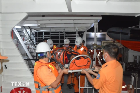 Thuyền viên tàu cứu nạn chuyên dụng SAR 413 đưa thuyền viên Khu Văn Khoan từ tàu SAR 413 lên bờ. (Nguồn: TTXVN phát)