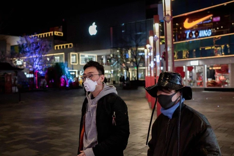 Người dân đeo khẩu trang đi ngang qua một cửa hàng Apple bên ngoài một trung tâm mua sắm vắng vẻ ở Bắc Kinh vào ngày 24/2. (Nguồn: AFP)