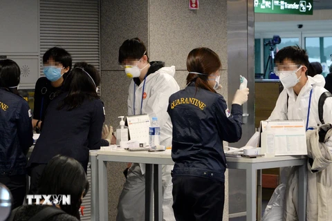Nhân viên tiến hành công tác kiểm dịch đối với hành khách tại sân bay Incheon, phía tây thủ đô Seoul, Hàn Quốc, ngày 23/3/2020. (Nguồn: Yonhap/TTXVN)