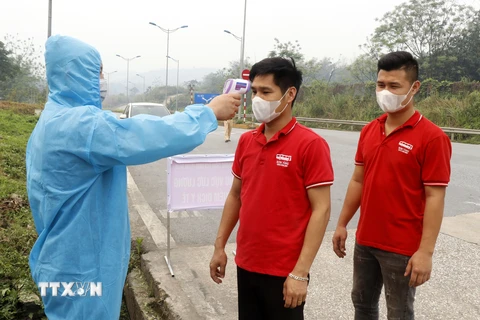 Người dân và hành khách được kiểm tra thân nhiệt tại chốt nút giao đường cao tốc Nội Bài-Lào Cai thuộc địa phận xã Xuân Giao, huyện Bảo Thắng (Km234). (Ảnh: Quốc Khánh/TTXVN)