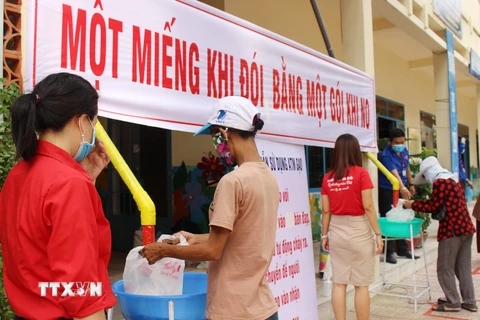 Người dân đến nhận gạo tại điểm "ATM gạo" phường Phước Tiến, mỗi người nhận 2 kg gạo/ngày. (Ảnh: Tiên Minh/TTXVN)