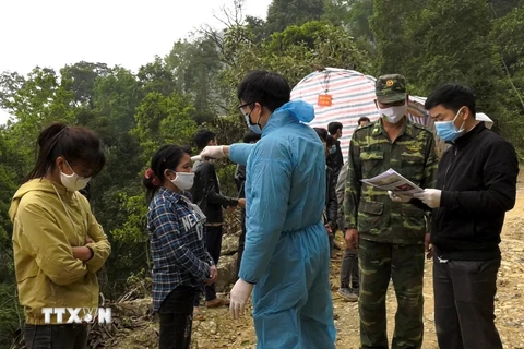 Cán bộ chiến sỹ đồn biên phòng Pha Long (huyện Mường Khương) kiểm tra thân nhiệt cho các công dân trở về tử Trung Quốc. (Ảnh: Quốc Khánh/TTXVN)
