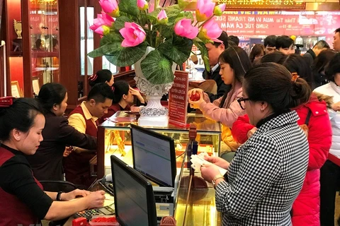 Khách hàng đang giao dịch vàng tại cửa hàng vàng bạc Bảo Tín Minh Châu, Hà Nội. (Ảnh: Đức Duy/Vietnam+)